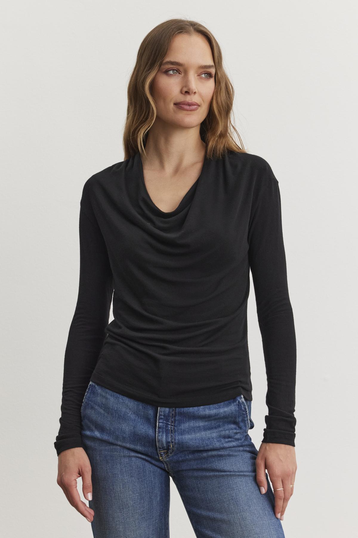   A person with long brown hair is wearing the PATTY TEE in black Tencel™ knit by Velvet by Graham & Spencer, along with blue jeans, standing against a plain white background. 