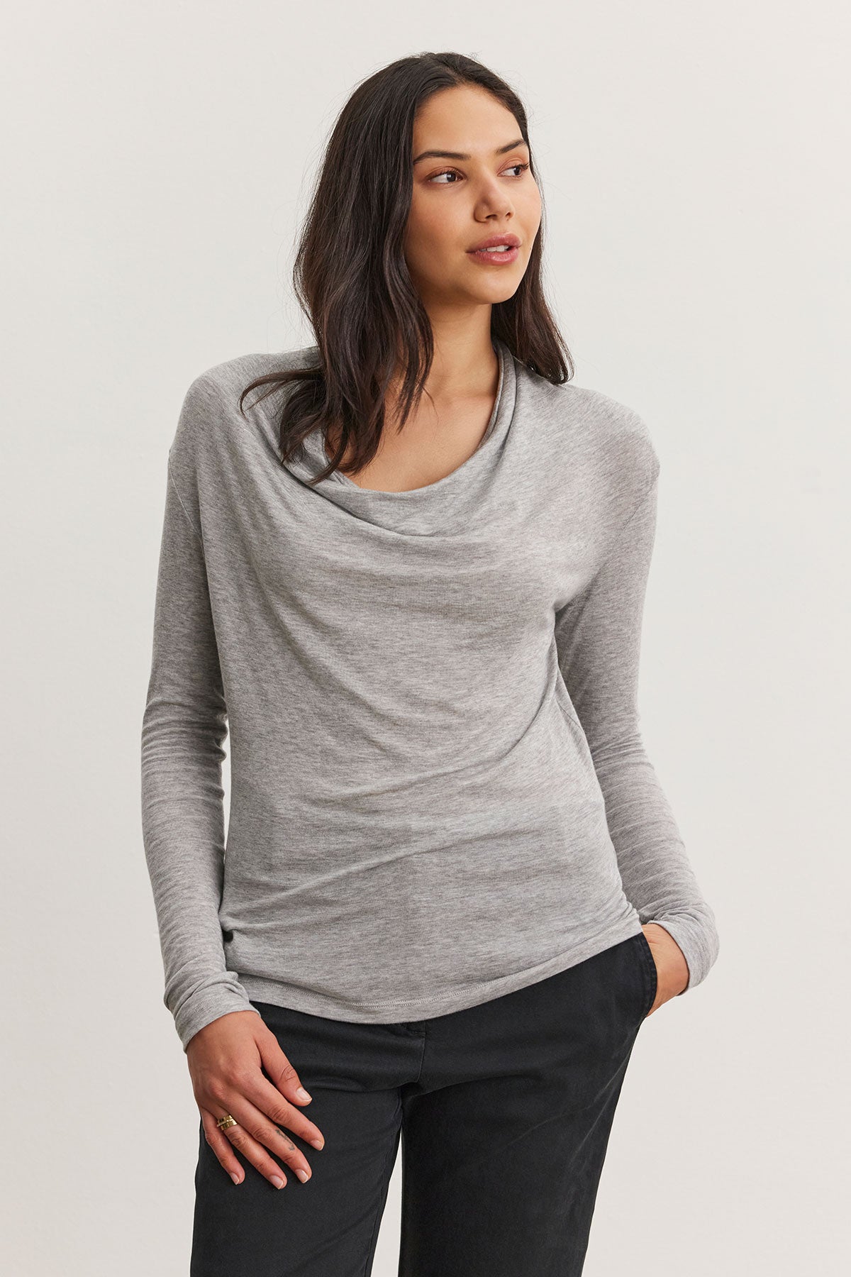   A person wearing a PATTY TEE gray Tencel™ knit cowl neck sweater by Velvet by Graham & Spencer and black pants stands against a plain background. 