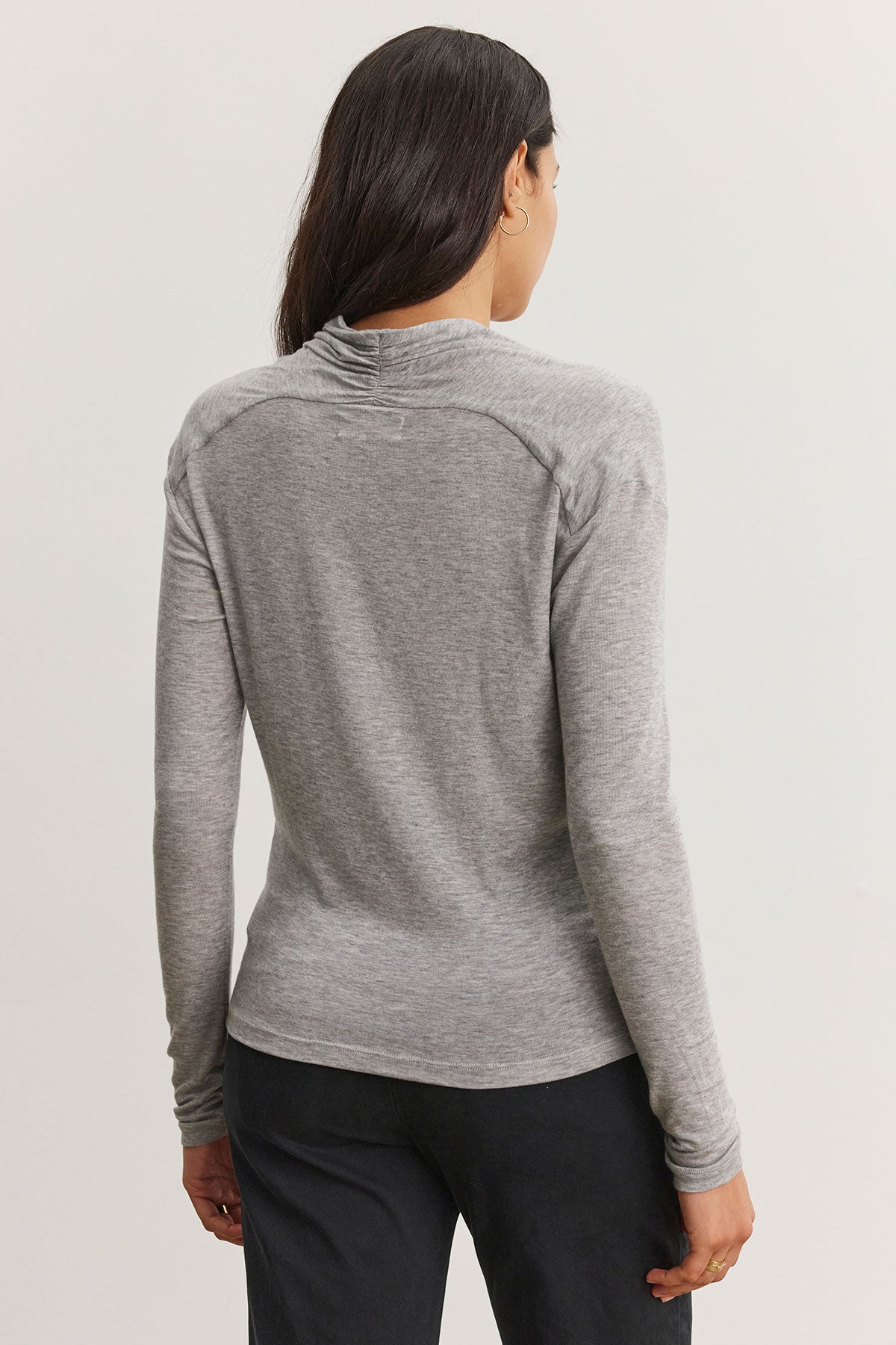 A person with long hair is seen from behind, wearing what appears to be Velvet by Graham & Spencer's gray PATTY TEE and black pants.-38301422715073