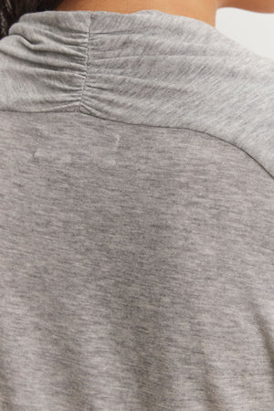 Close-up of the back of a person's neck and shoulder wearing a gray cowl-neck garment, crafted from soft Tencel™ knit, known as the PATTY TEE by Velvet by Graham & Spencer.