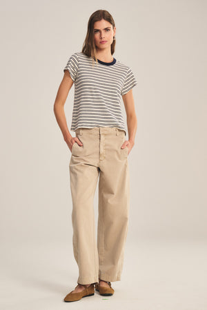 A woman faces forward against a plain light background, wearing the TENLEY PANT by Velvet by Graham & Spencer—high-waisted, relaxed fit cotton twill pants—with a striped t-shirt and brown shoes.