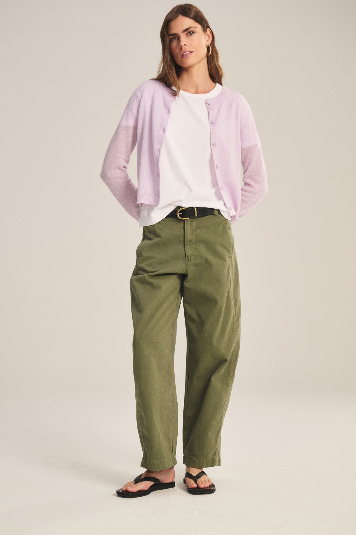 A woman wears the TENLEY PANT by Velvet by Graham & Spencer in a relaxed fit, paired with a light purple cardigan, white t-shirt, black belt, and black sandals against a neutral background.-40808733409473