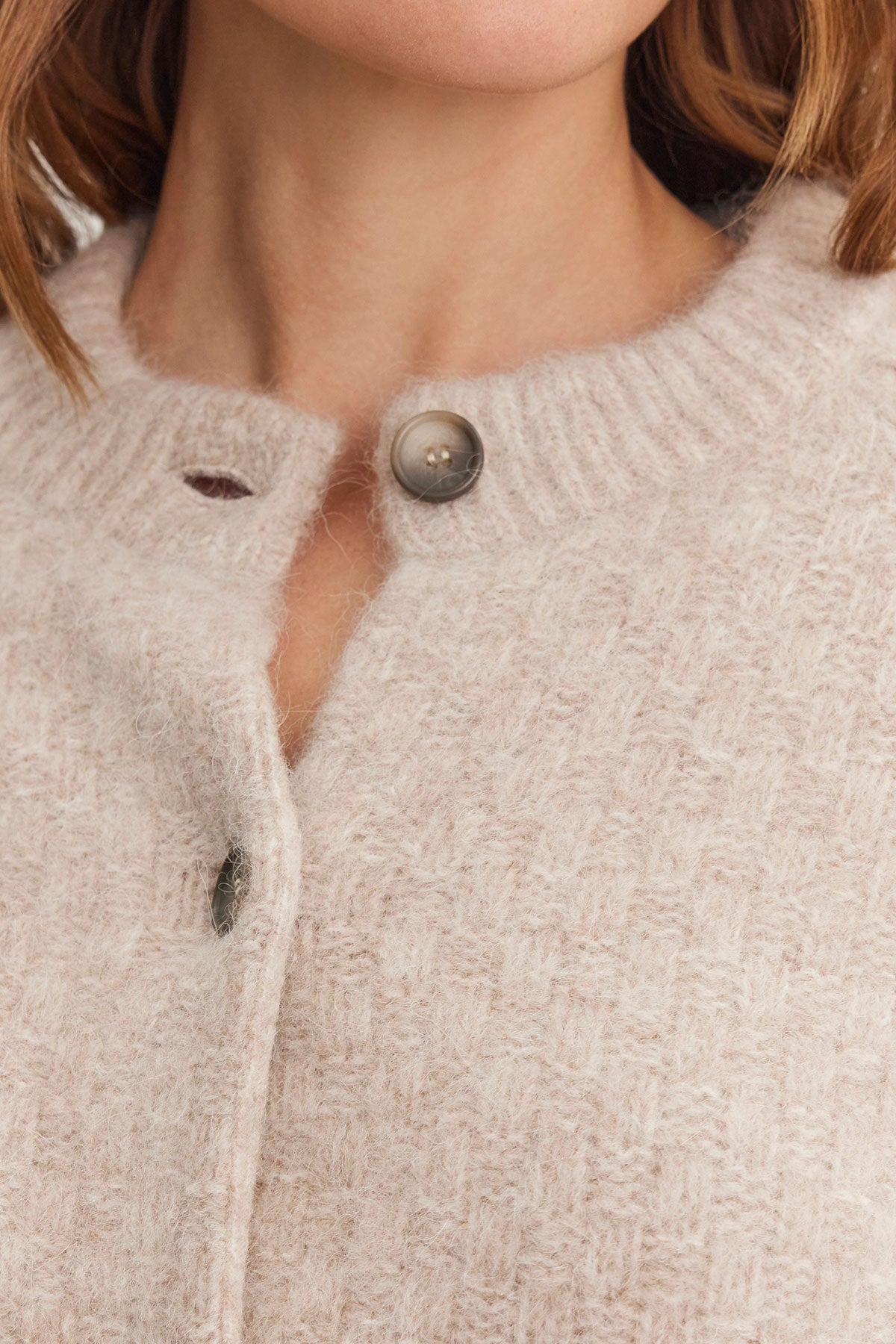 A close-up of an individual wearing the CHANTAL ALPACA CARDIGAN in a light beige hue, designed by Velvet by Graham & Spencer, showcasing ribbed trims and a five-button front.-38301315399873