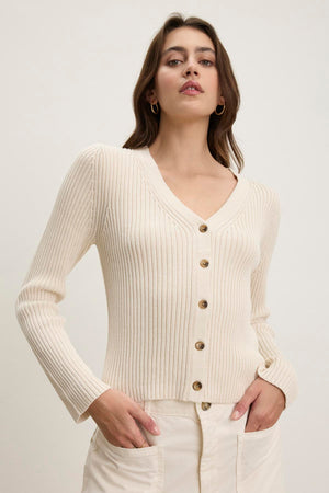 A person wearing the HYDIE CARDIGAN by Velvet by Graham & Spencer and cream pants stands against a plain background.