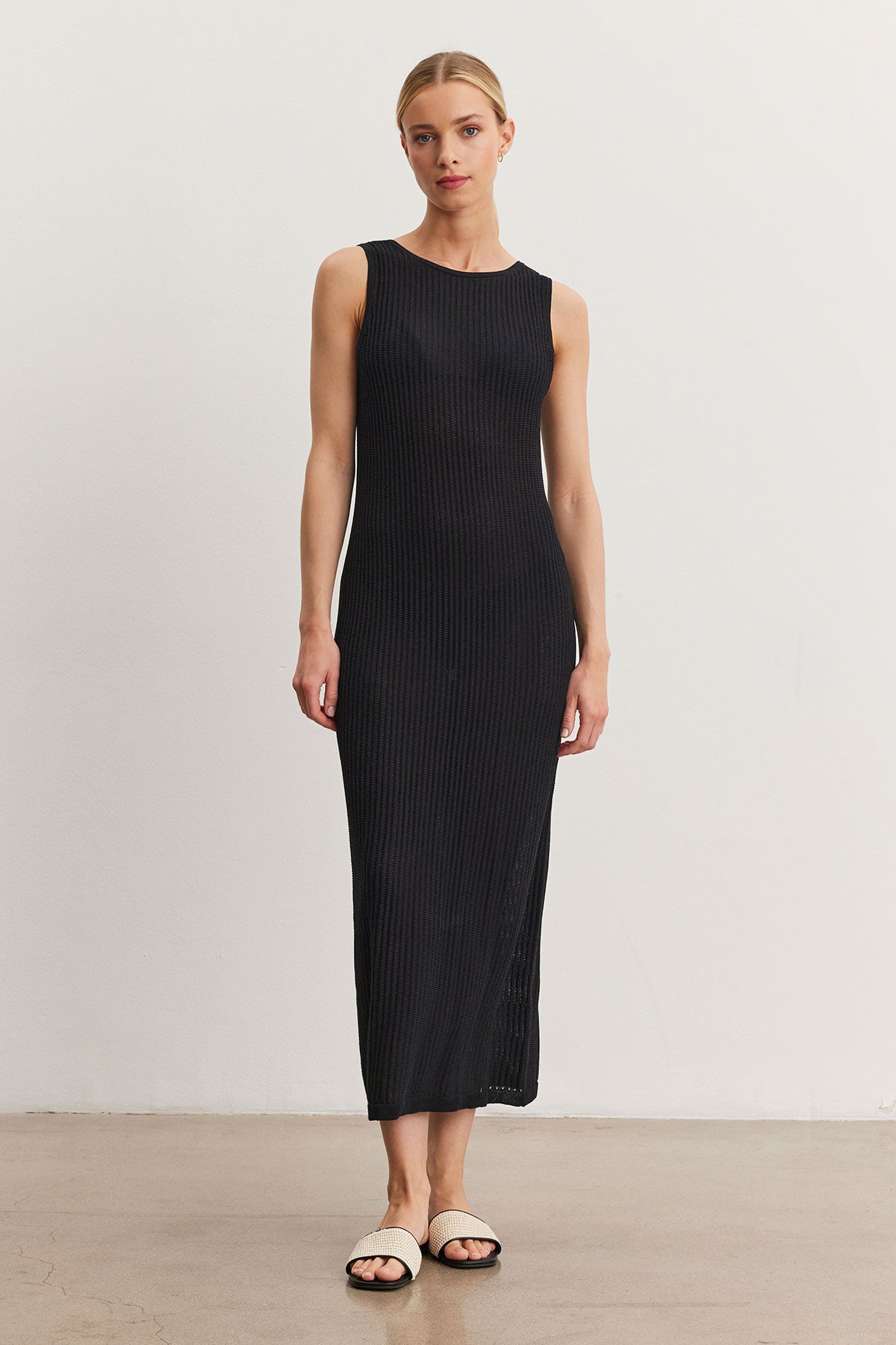 A woman stands in a neutral pose wearing a Velvet by Graham & Spencer Callen Dress, black and ribbed, paired with open-toed flat sandals, against a plain light background.-36998731858113