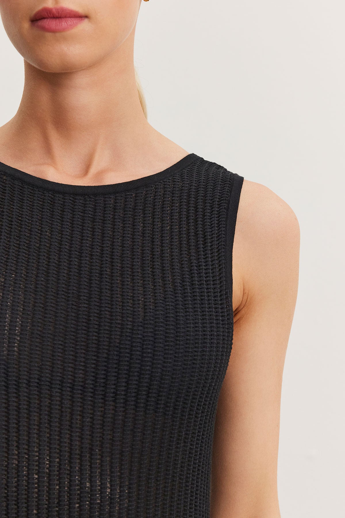   Close-up of a woman wearing a ribbed black sleeveless Velvet by Graham & Spencer CALLEN DRESS, focusing on the garment's texture and her shoulder. 