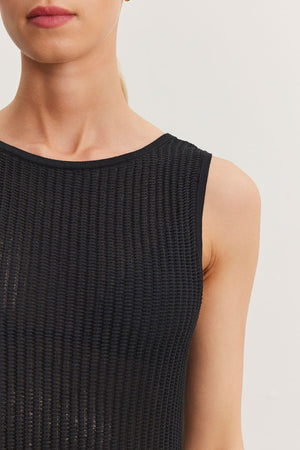 Close-up of a woman wearing a ribbed black sleeveless Velvet by Graham & Spencer CALLEN DRESS, focusing on the garment's texture and her shoulder.