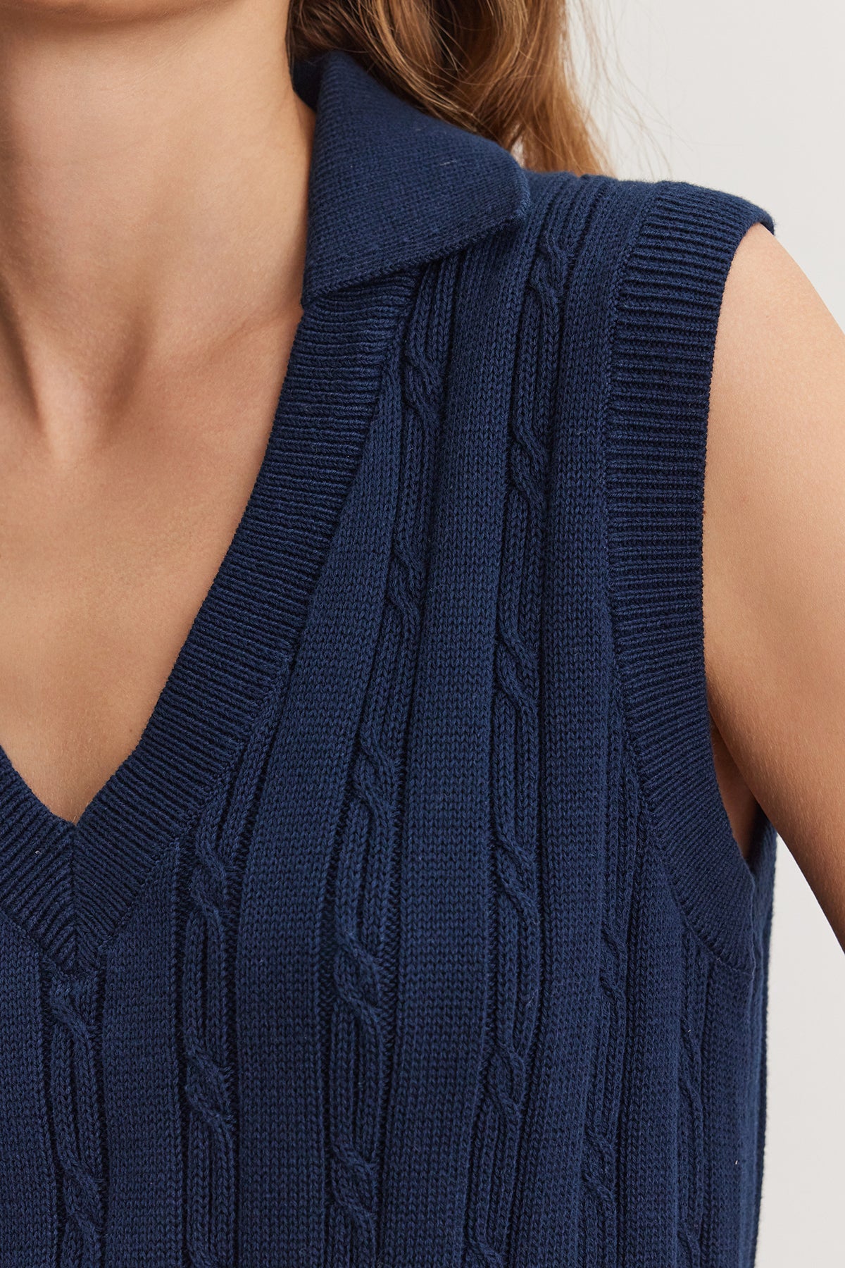 Close-up of a woman wearing a dark blue WENDY SWEATER VEST by Velvet by Graham & Spencer, with a collared shirt underneath, focusing on the detailed texture of the knit fabric.-36909568557249