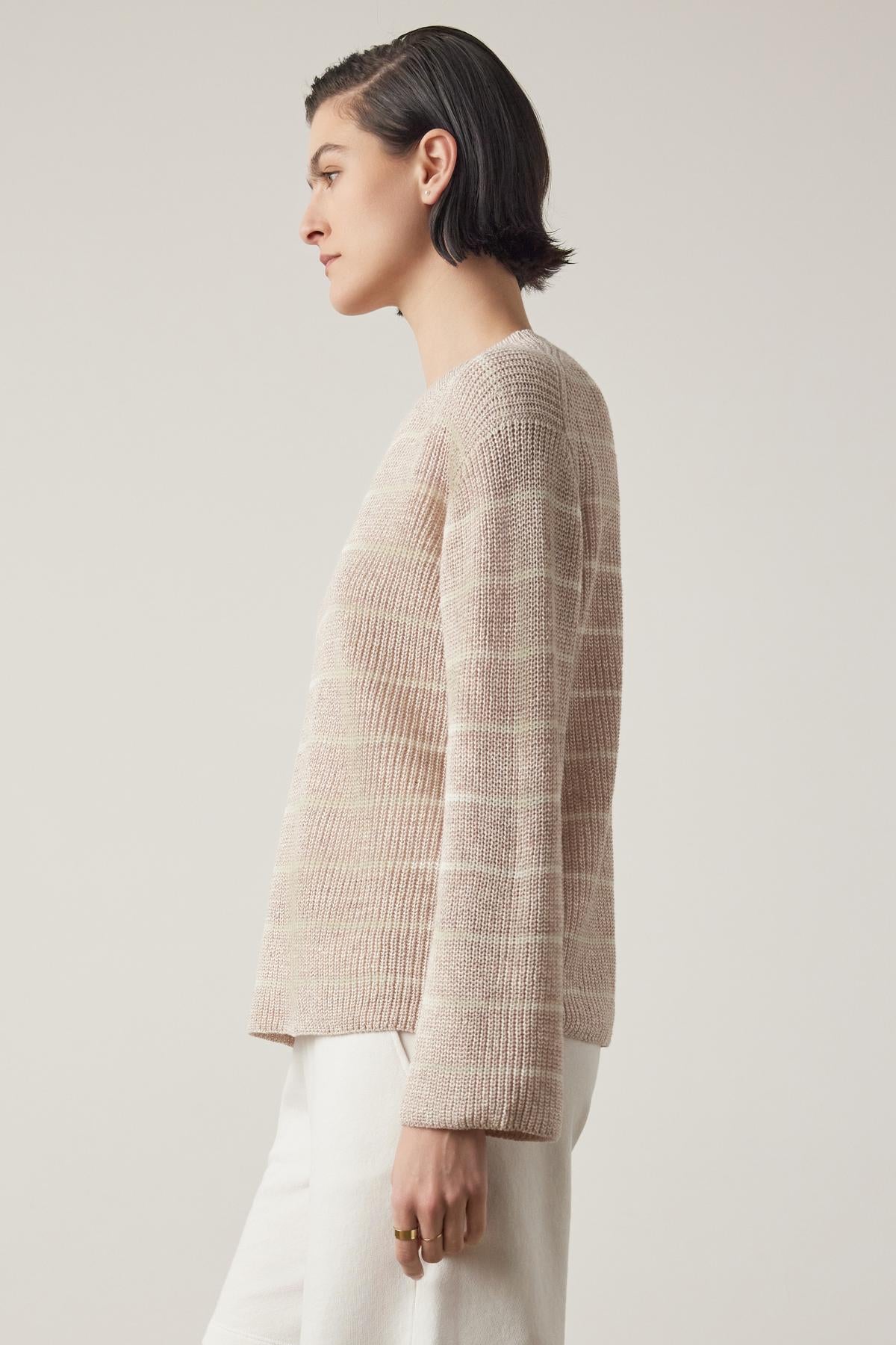 Side profile of a person with short dark hair wearing a beige textured Indio Linen Sweater from Velvet by Jenny Graham and white pants against a light background.-36863294996673