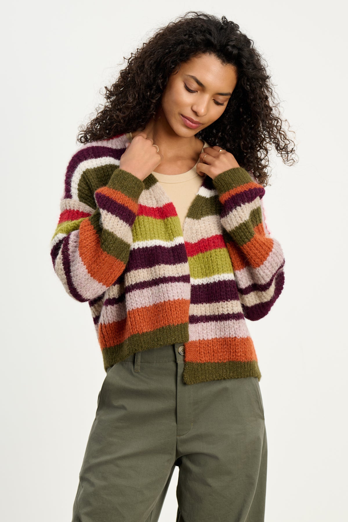 A person wears the RANYA ALPACA CARDIGAN by Velvet by Graham & Spencer, an open alpaca-blend piece in earthy tones, paired with green pants against a plain background, highlighting this cozy layering essential.-39742382833857