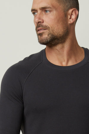 A man wearing a Velvet by Graham & Spencer GLEN THERMAL CREW black long-sleeved top.