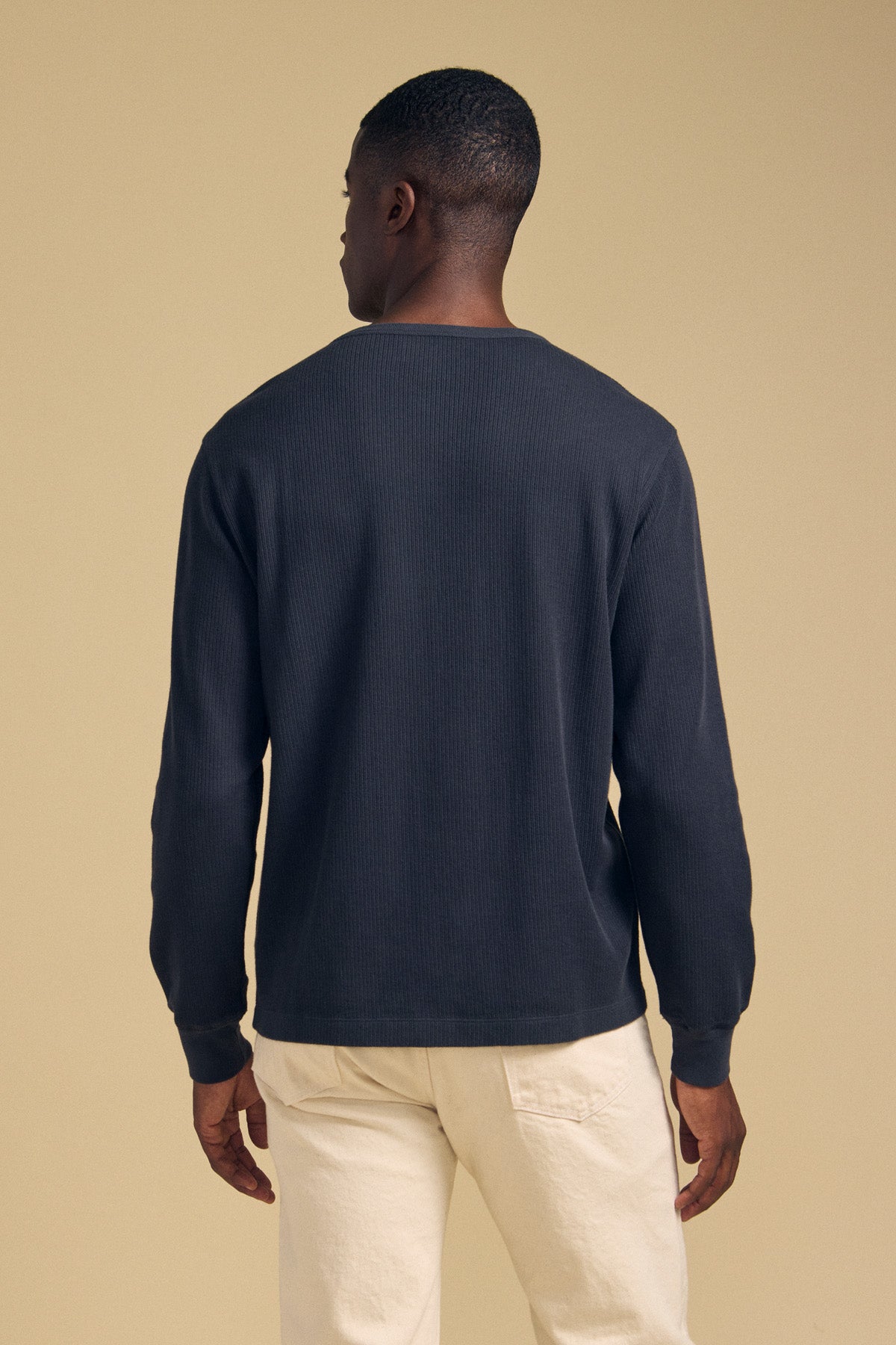 Back view of a person wearing a dark blue CHANCE THERMAL HENLEY and cream-colored pants.-46288227303617