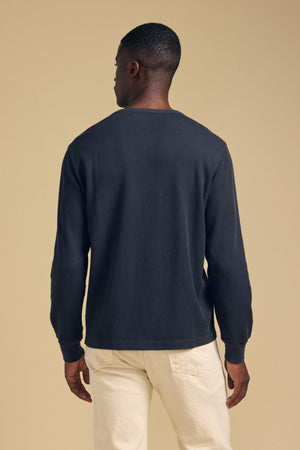 Back view of a person wearing a dark blue CHANCE THERMAL HENLEY and cream-colored pants.