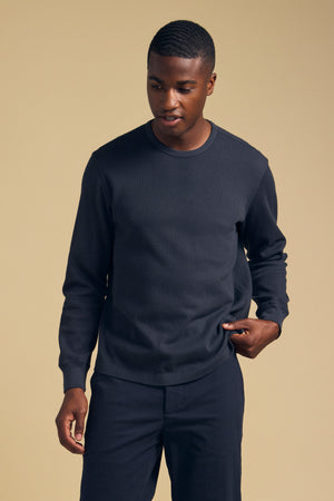 A man wearing a dark-colored, long-sleeved DARIEL THERMAL PULLOVER by Velvet by Graham & Spencer for cold-weather wear.