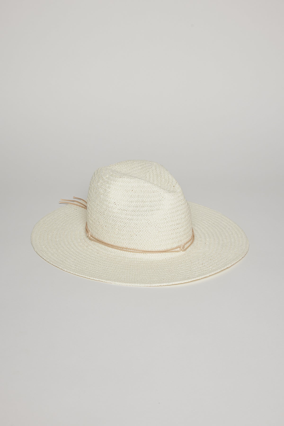   A white, wide-brimmed TRAVELER CONTINENTAL HAT by Velvet by Graham & Spencer with a beige band around the base of the crown, placed on a light grey surface. 