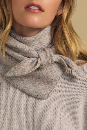 Close-up of a woman wearing a light gray speckled knit sweater and the Velvet by Graham & Spencer KARLA SCARF, a matching wool blend accessory elegantly knotted at the neck for cozy layering.