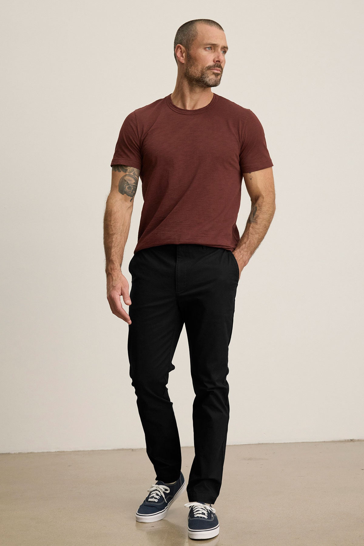 Man with short hair and a trimmed beard wears the MADDOX PANT by Velvet by Graham & Spencer, paired with a maroon t-shirt and navy sneakers, standing against a plain light background for a polished look.-39599113175233