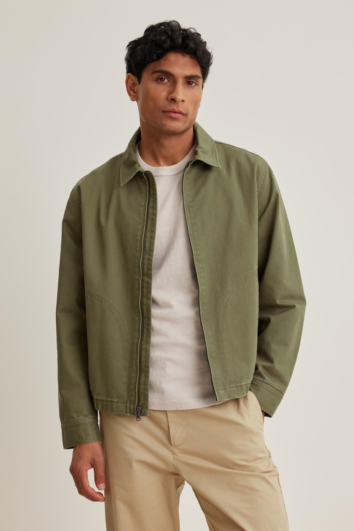   A person wearing the COLLINS JACKET by Velvet by Graham & Spencer over a white shirt and beige pants stands against a plain background. 