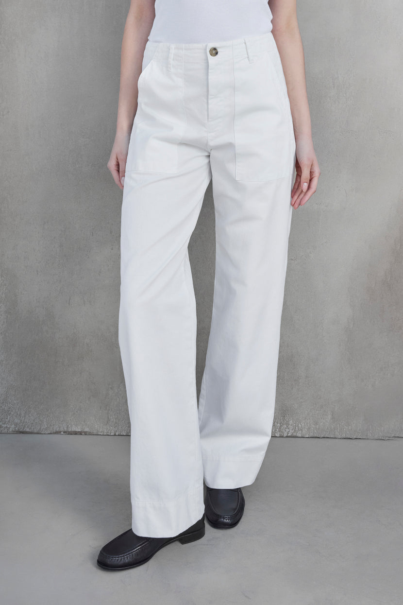 Person wearing high-waisted, wide-leg VENTURA PANT from Velvet by Jenny Graham, paired with a white top and black shoes, standing against a plain gray background.