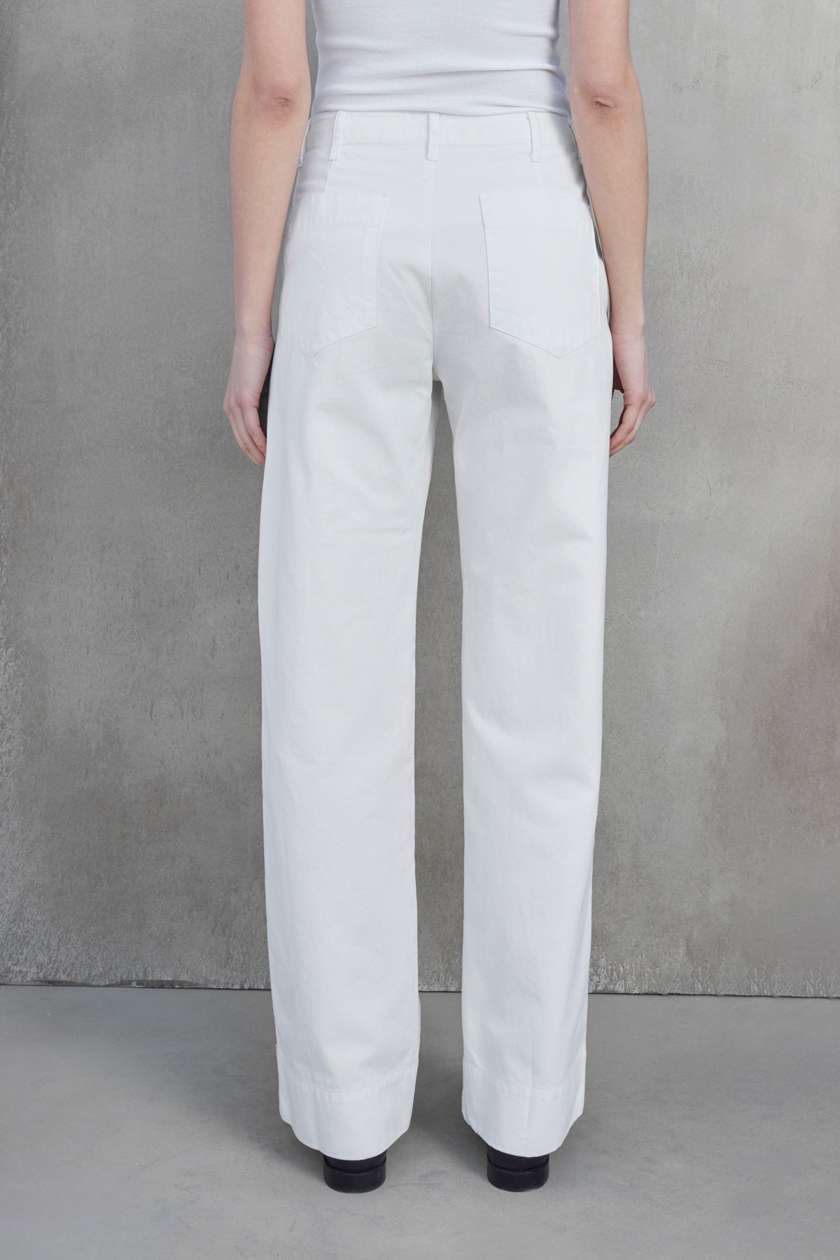 Rear view of a person wearing the VENTURA PANT — white high-waisted, wide-leg pants made from cotton twill by Velvet by Jenny Graham — paired with a matching top, standing against a neutral gray background.-37659921907905