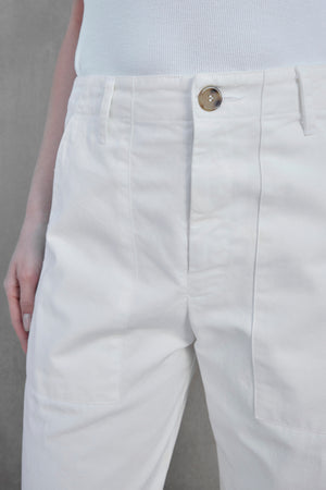 Close-up view of a person wearing the VENTURA PANT by Velvet by Jenny Graham, featuring white, high-waisted wide-leg pants with a single button closure and a tucked-in white top. The outfit exudes a subtle utilitarian vibe, perfect for both casual and chic occasions.