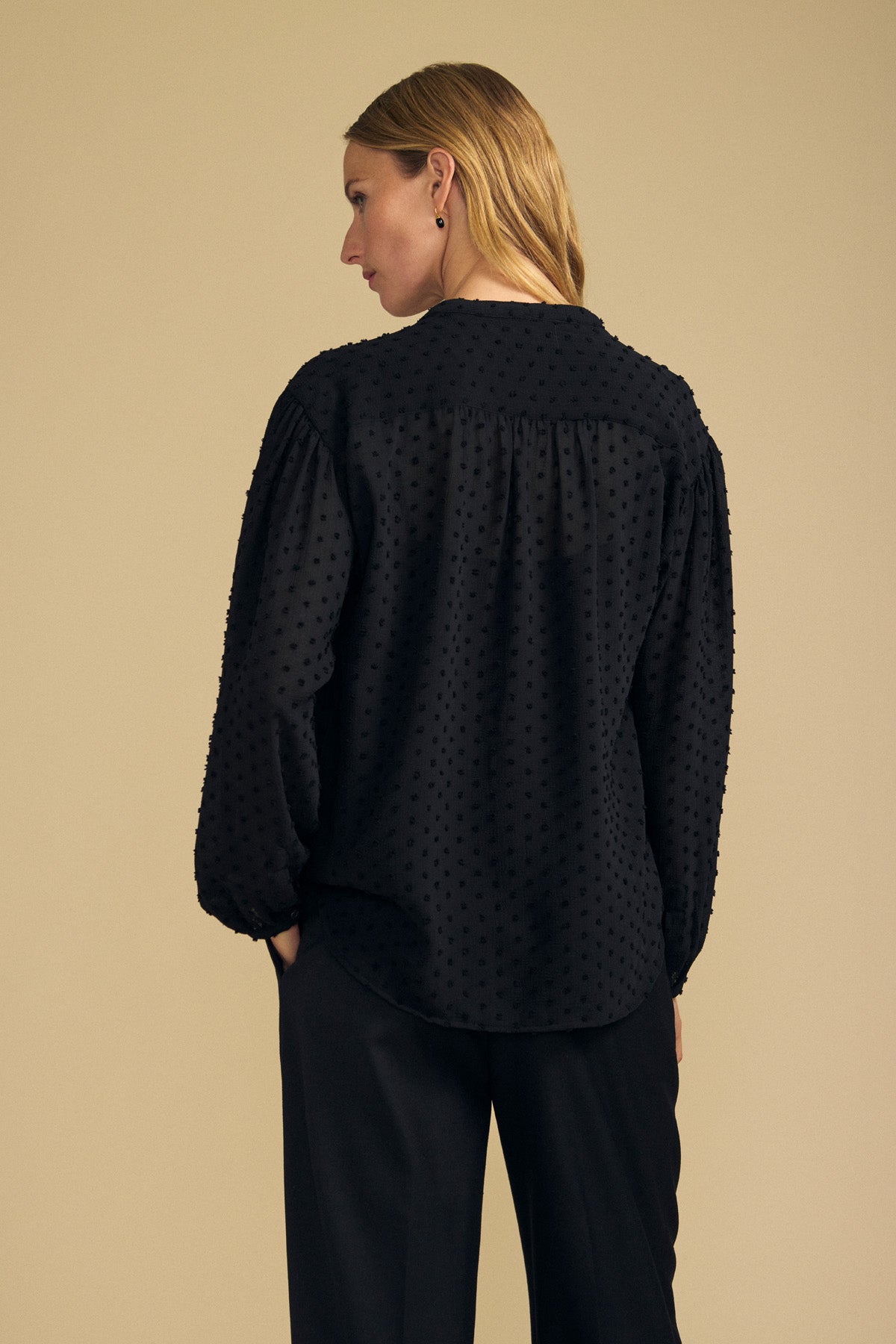 Back view of a woman wearing the black ADRIANA TEXTURED CREPE TOP, featuring a button-front design in textured crepe fabric with a gathered back yoke.-46489821970625