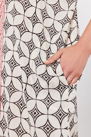 Close-up of a hand with a ring, touching a Velvet by Graham & Spencer Odessa Kaftan Dress with a black geometric pattern.