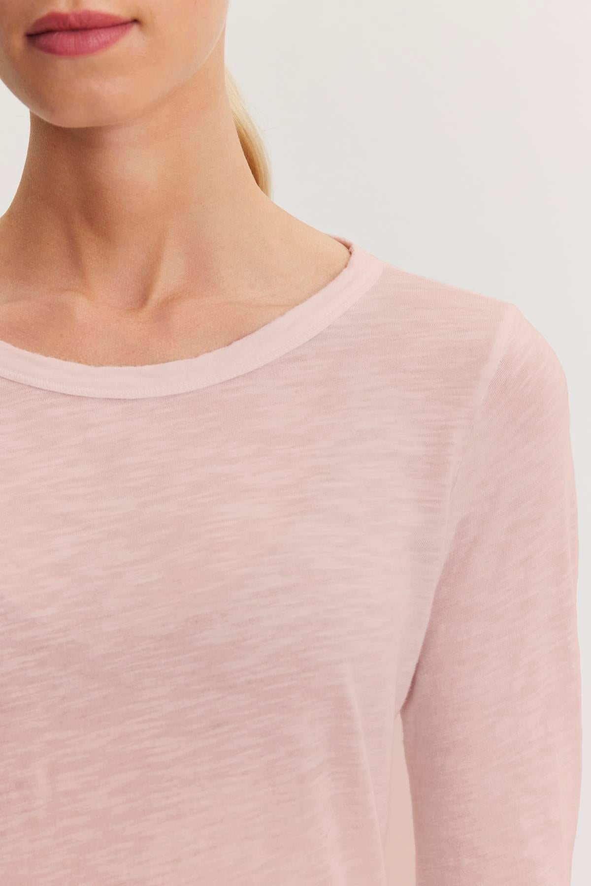   A person is wearing the LIZZIE TEE by Velvet by Graham & Spencer, a light pink cotton slub long sleeve shirt, with their upper chest and face partially out of frame. 