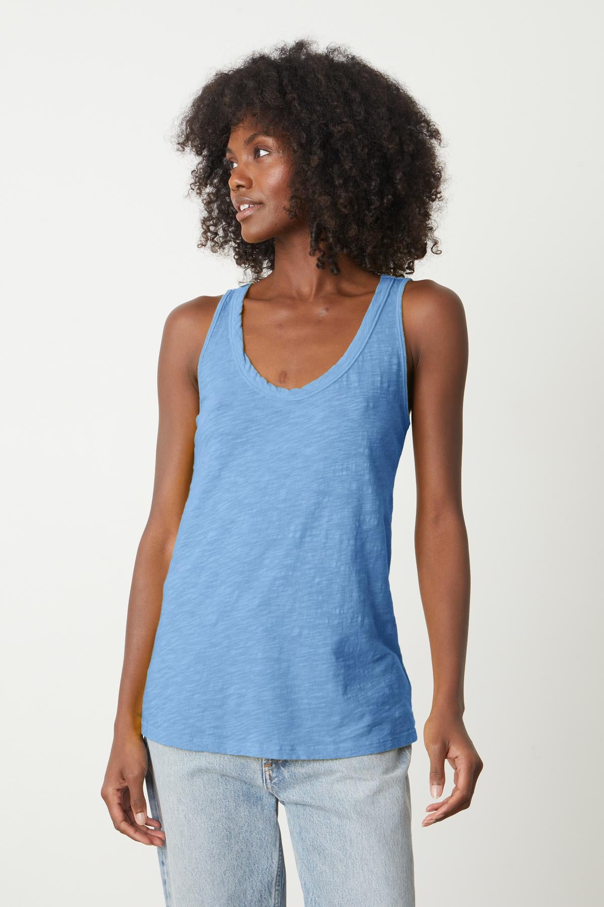  A woman wearing a Velvet by Graham & Spencer JOY ORIGINAL SLUB SCOOP NECK TANK in blue, with a soft cotton fabric and flattering arm hole. 