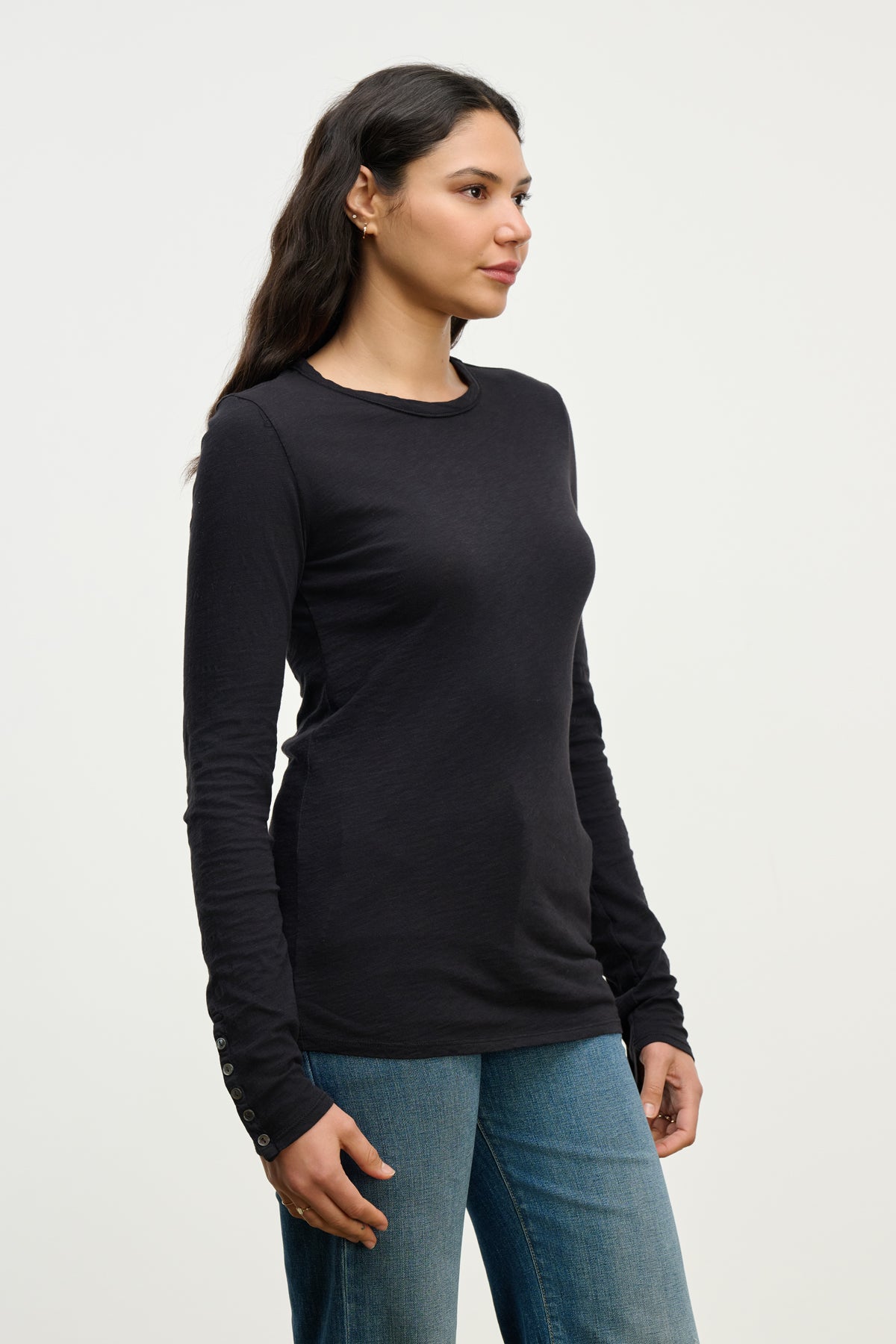 A woman stands facing left, wearing the KELSEY TEE by Velvet by Graham & Spencer with blue jeans against a plain light background.-39815225802945