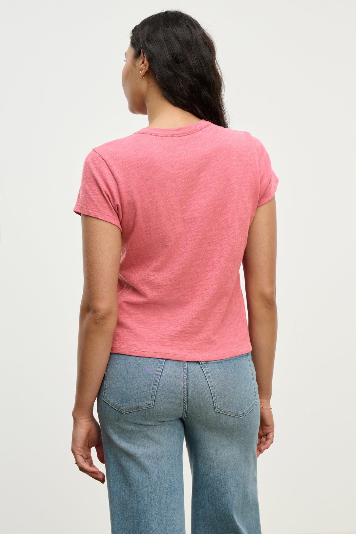   Someone wearing the MARIE TEE by Velvet by Graham & Spencer and blue jeans stands against a plain background, highlighting a relaxed, boxy fit. 