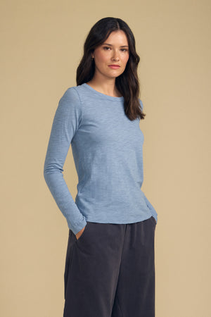 Three-quarter view of LIZZIE Originals cotton slub long sleeve crew neck tee in light blue, hands in pockets