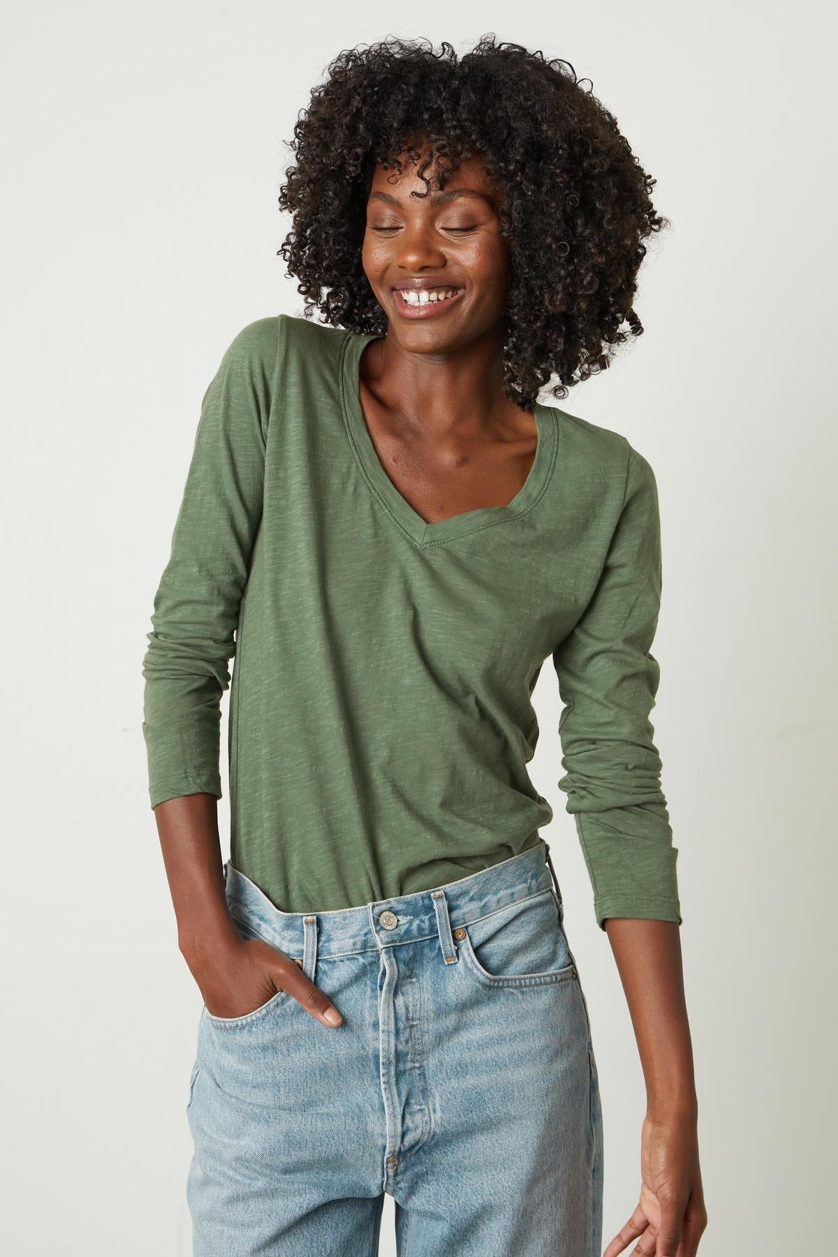  A woman wearing a green Velvet by Graham & Spencer Blaire Original Slub Tee and jeans. 