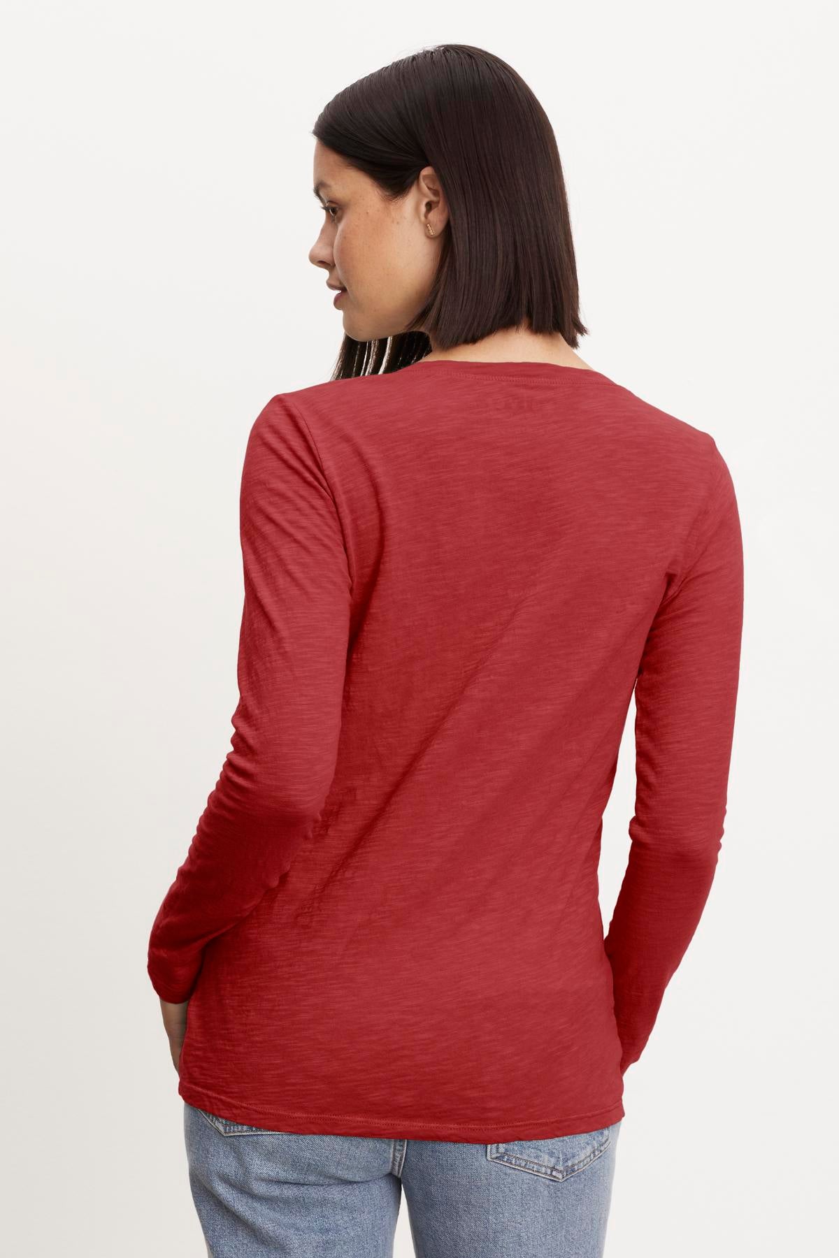   The back view of a woman wearing a red long-sleeved v-neck Blaire Original Slub Tee made from whisper-soft cotton, turning it into a forever piece by Velvet by Graham & Spencer. 