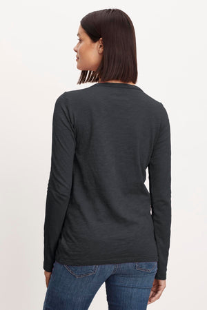 The back view of a woman wearing LIZZIE ORIGINAL SLUB LONG SLEEVE TEE by Velvet by Graham & Spencer jeans and a long-sleeved shirt.