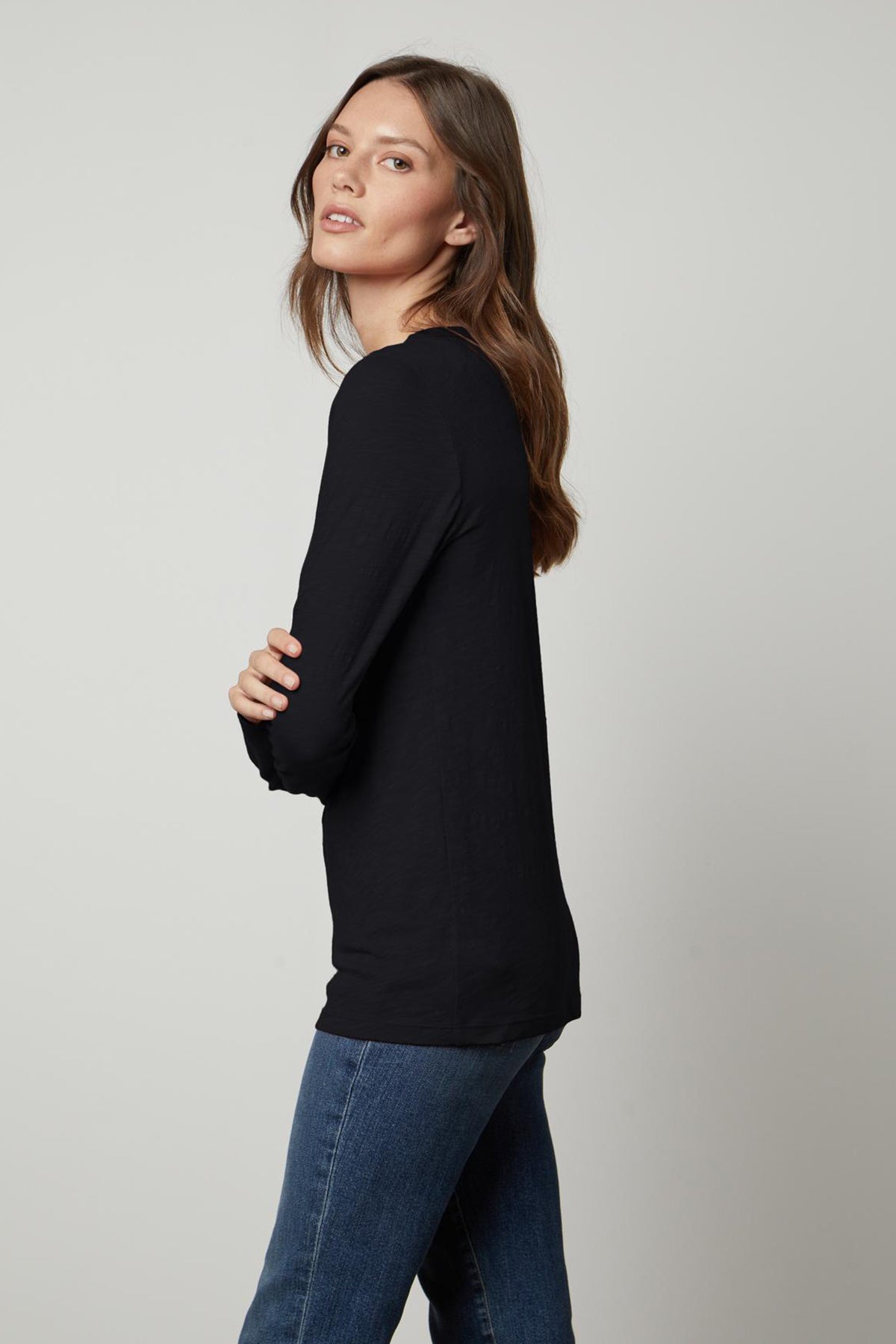 A woman wearing a black LIZZIE ORIGINAL SLUB LONG SLEEVE TEE made of cotton, paired with jeans from Velvet by Graham & Spencer.-35629837648065