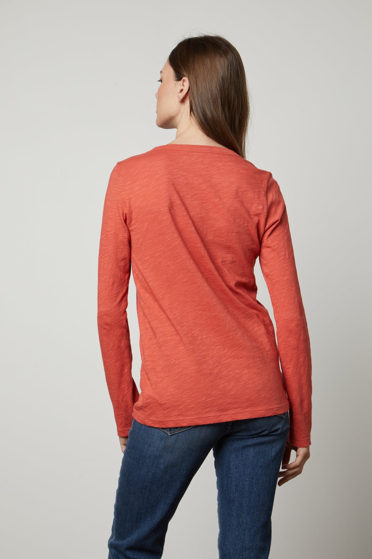   The back view of a woman wearing an orange LIZZIE ORIGINAL SLUB LONG SLEEVE TEE made by Velvet by Graham & Spencer. 