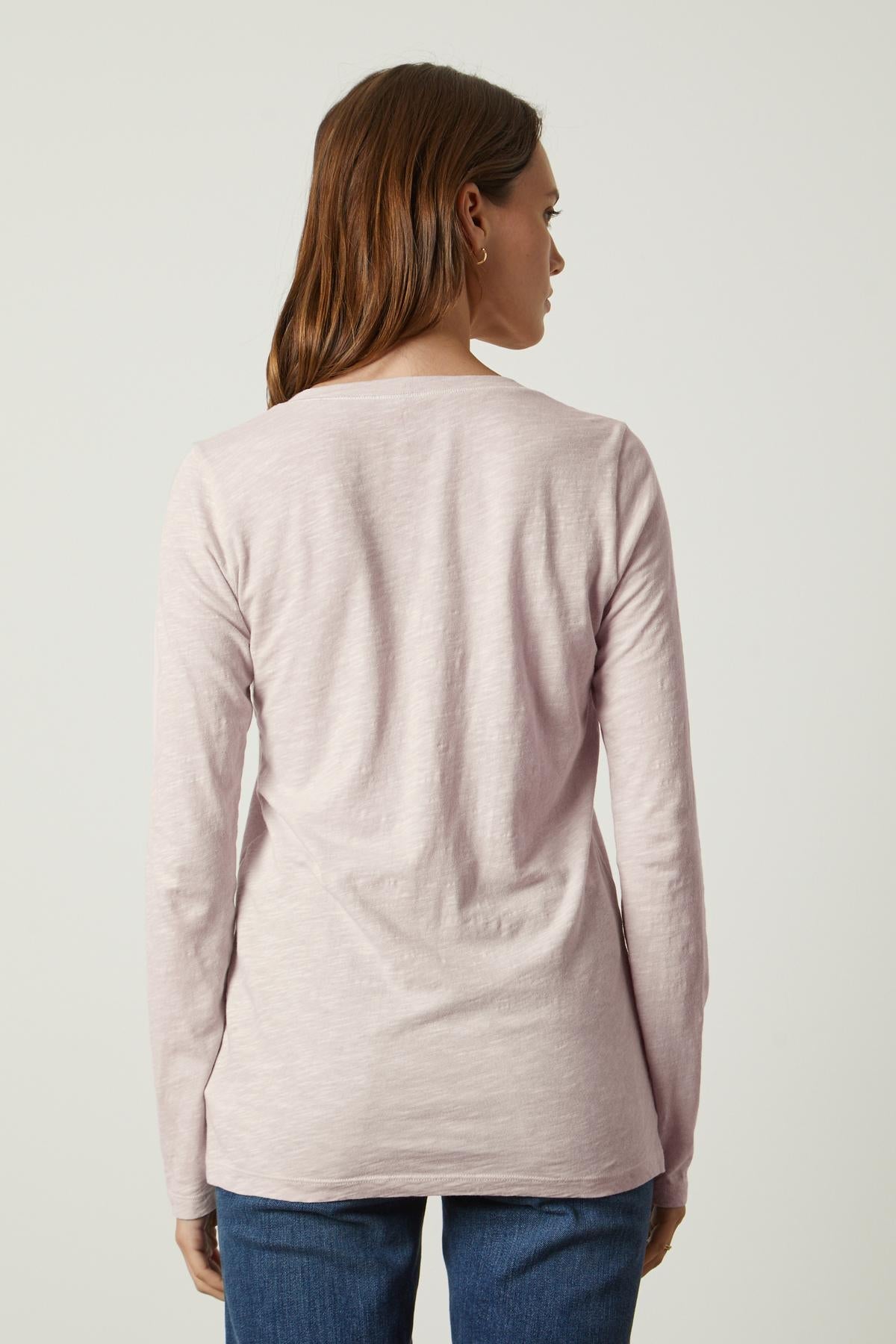   The back view of a woman wearing a long-sleeved pink BLAIRE ORIGINAL SLUB TEE made by Velvet by Graham & Spencer. 