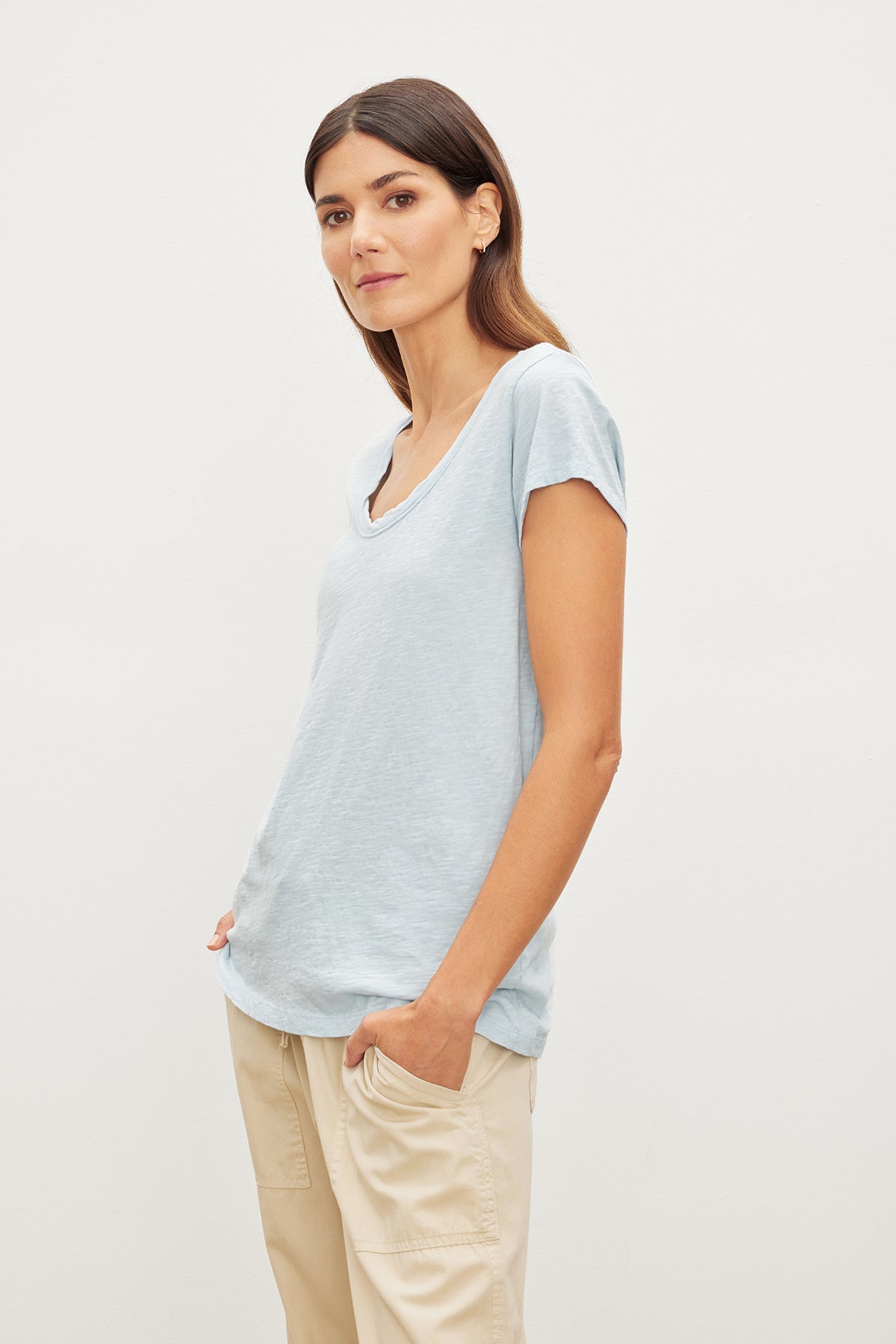 Woman in a Velvet by Graham & Spencer KIRA ORIGINAL SLUB SCOOP NECK TEE and beige pants standing against a white background, looking at the camera.-35982850425025