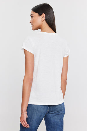 The back view of a woman wearing a white Velvet by Graham & Spencer KIRA ORIGINAL SLUB SCOOP NECK TEE and jeans.
