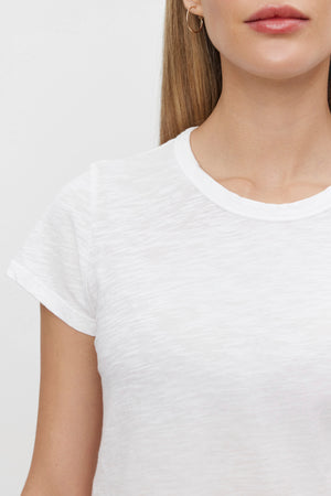 Close-up of a person wearing the MARIE TEE by Velvet by Graham & Spencer, featuring a small hoop earring perfect for a casual occasion. They have long, straight hair, and their face is partially visible.