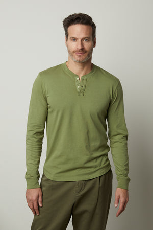 A man wearing a green Velvet by Graham & Spencer Braden Henley t-shirt.