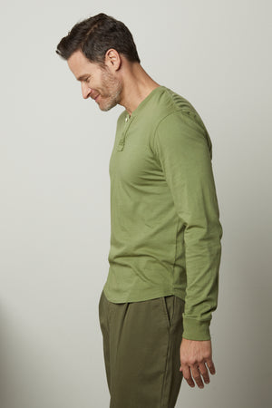 A man wearing the Velvet by Graham & Spencer BRADEN HENLEY shirt and green pants.