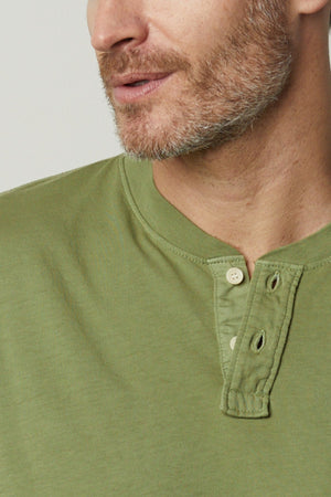 A man wearing a green Velvet by Graham & Spencer Braden Henley shirt.