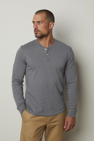 A man dressed in a Velvet by Graham & Spencer Braden henley shirt and khaki pants made from cotton fabric.