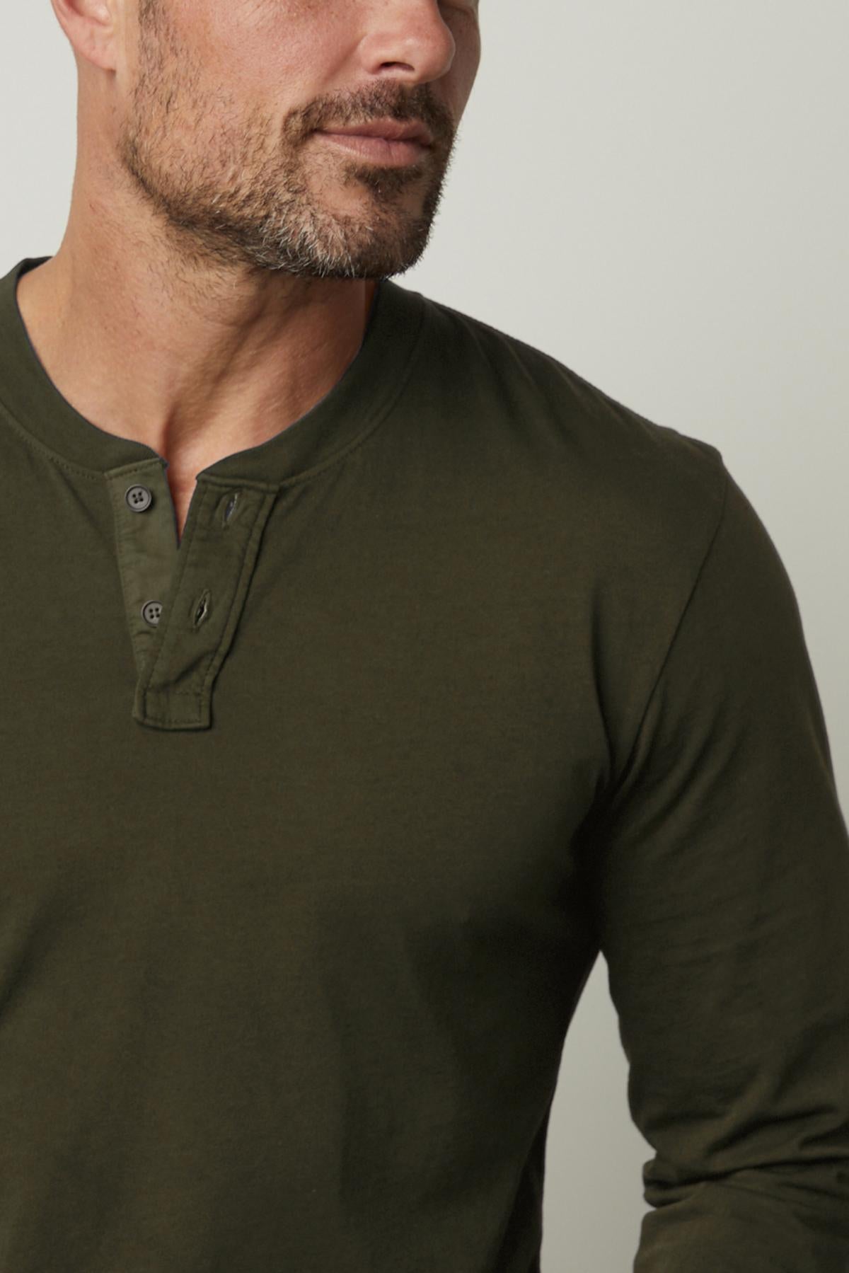   A man wearing a green Velvet by Graham & Spencer Braden Henley shirt made of lightweight cotton fabric. 
