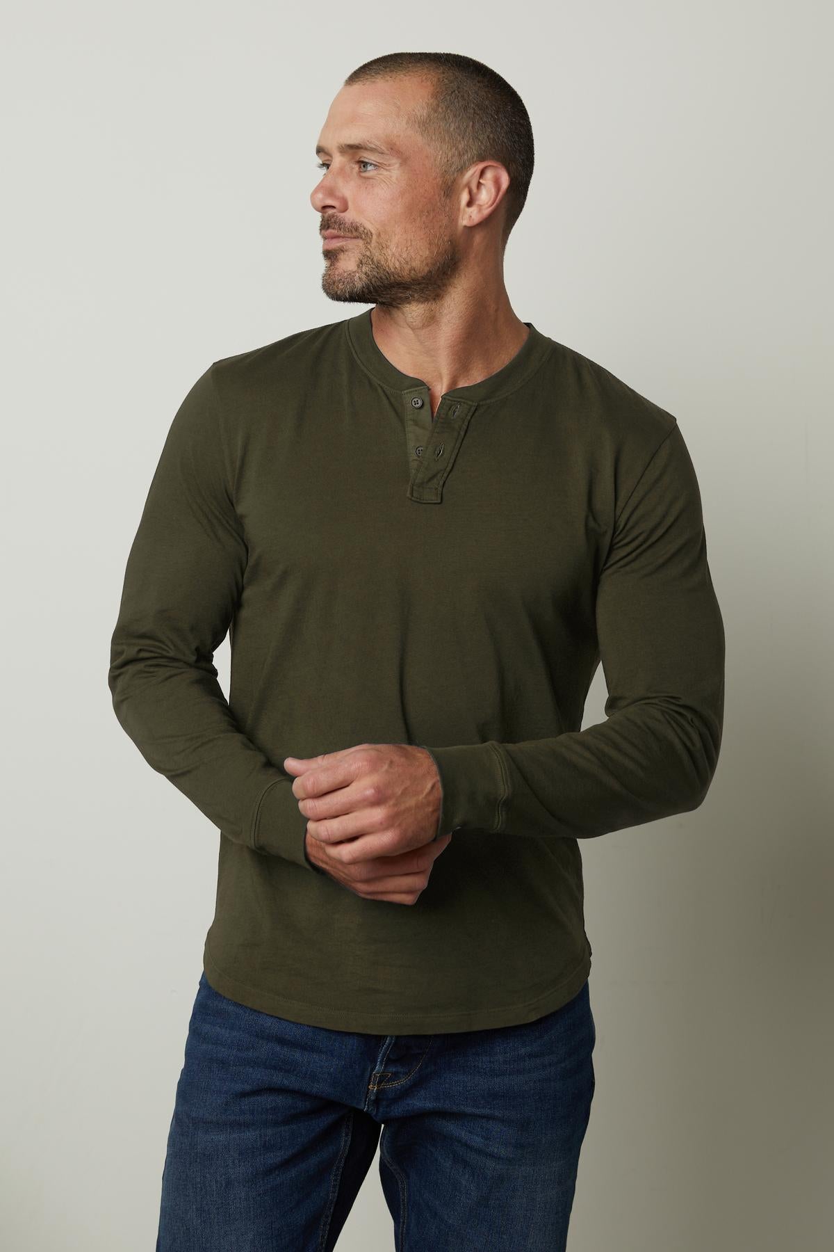 A man wearing a lightweight green BRADEN HENLEY t-shirt made of cotton fabric by Velvet by Graham & Spencer.-35547527020737