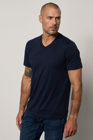 a man wearing a navy Velvet by Graham & Spencer MARSHALL V-NECK TEE and jeans.