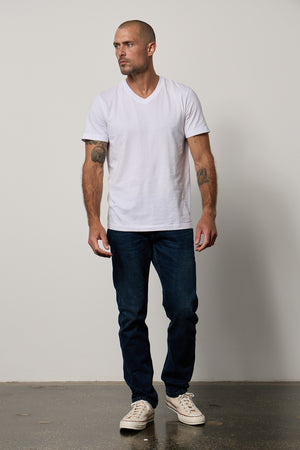 A man wearing a white Velvet by Graham & Spencer MARSHALL V-NECK TEE and jeans.