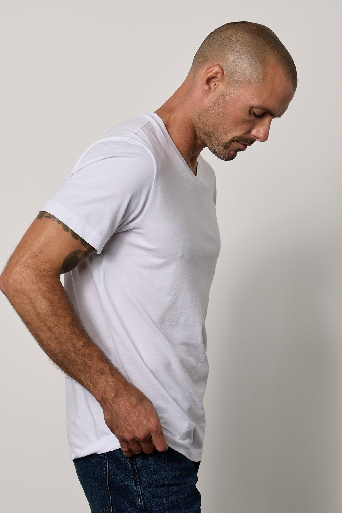   a man wearing a white Velvet by Graham & Spencer MARSHALL V-NECK TEE and jeans. 